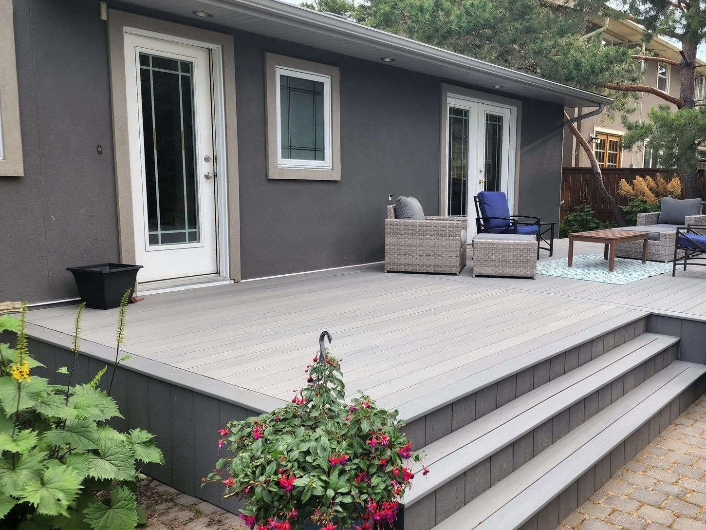 Grey deck with wide steps, seating and flowering planters